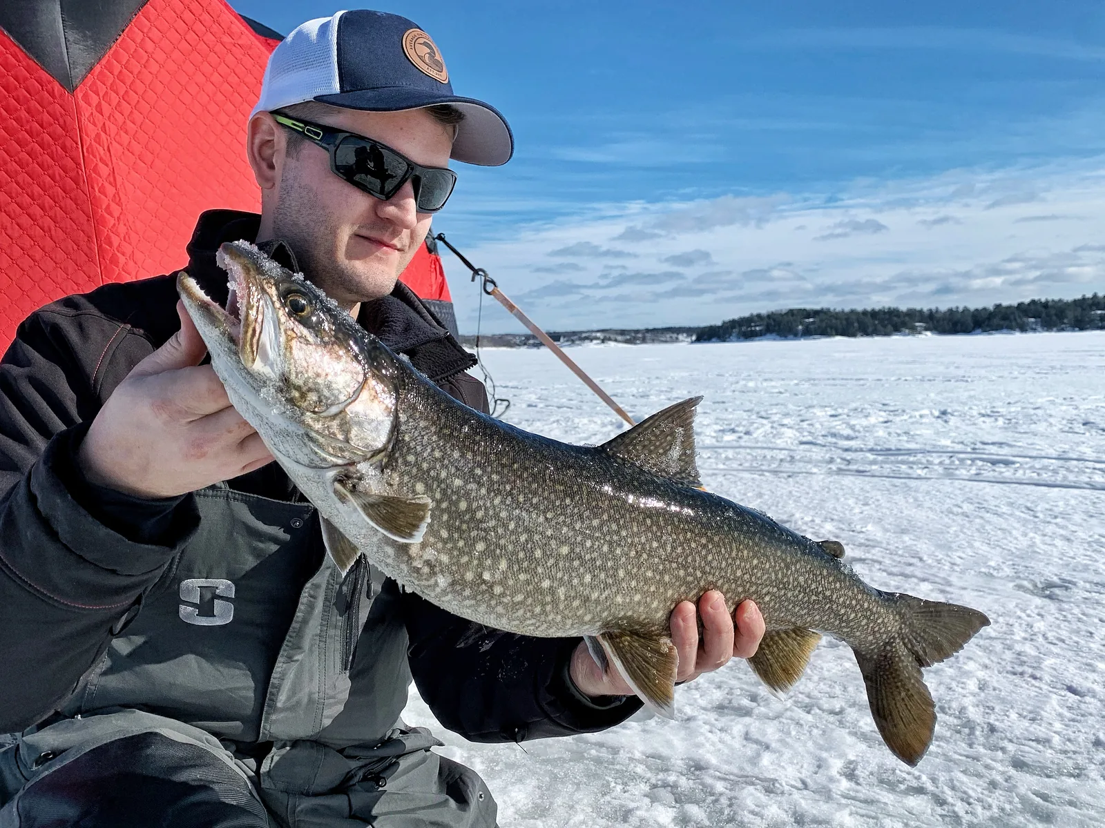 Jesse from Fishing Loons holding a lake trout while fishing.