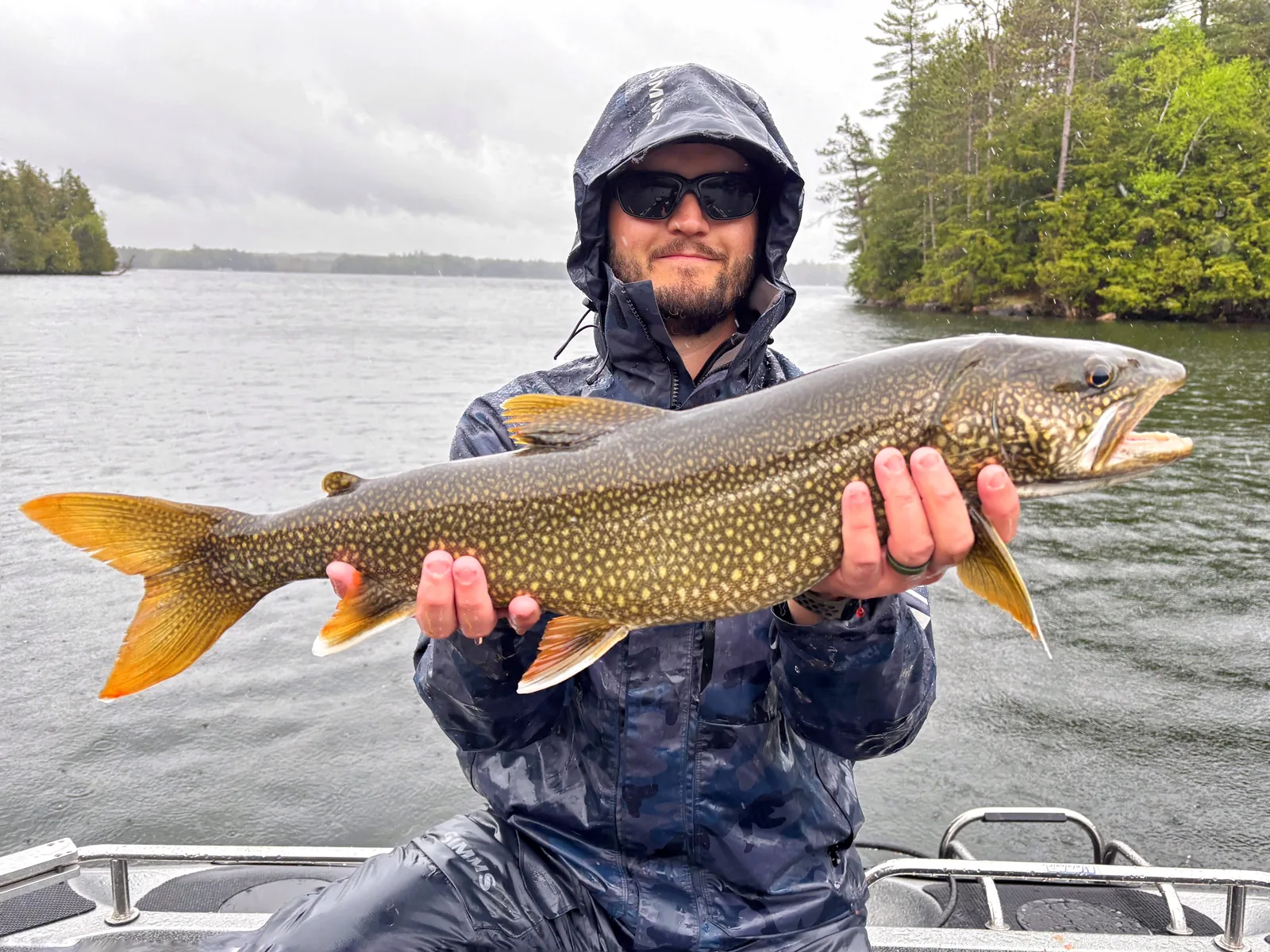 Jesse from Fishing Loons holding a lake trout while fishing.