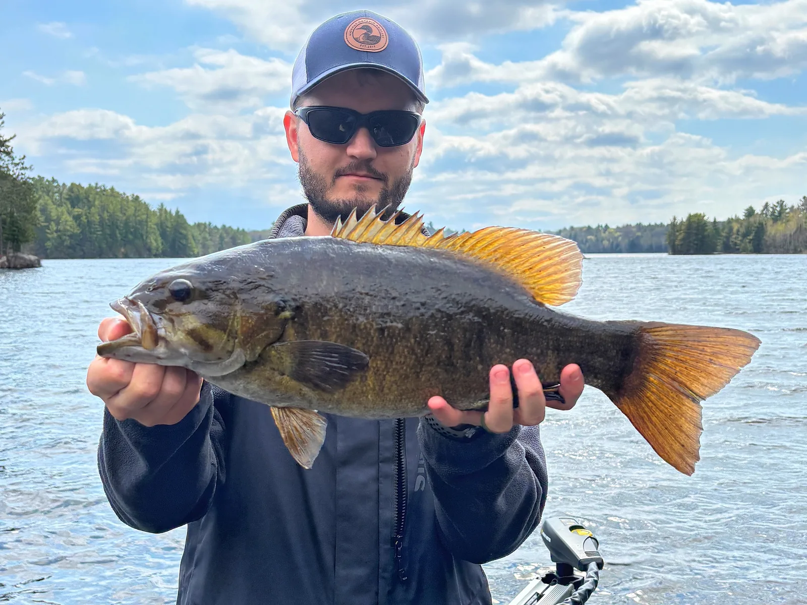 Jesse from Fishing Loons holding a smallmouth bass while fishing.